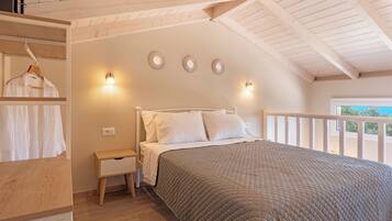 A bedroom with a wooden ceiling, a bed with white bedding, a bedside table, and a wardrobe.
