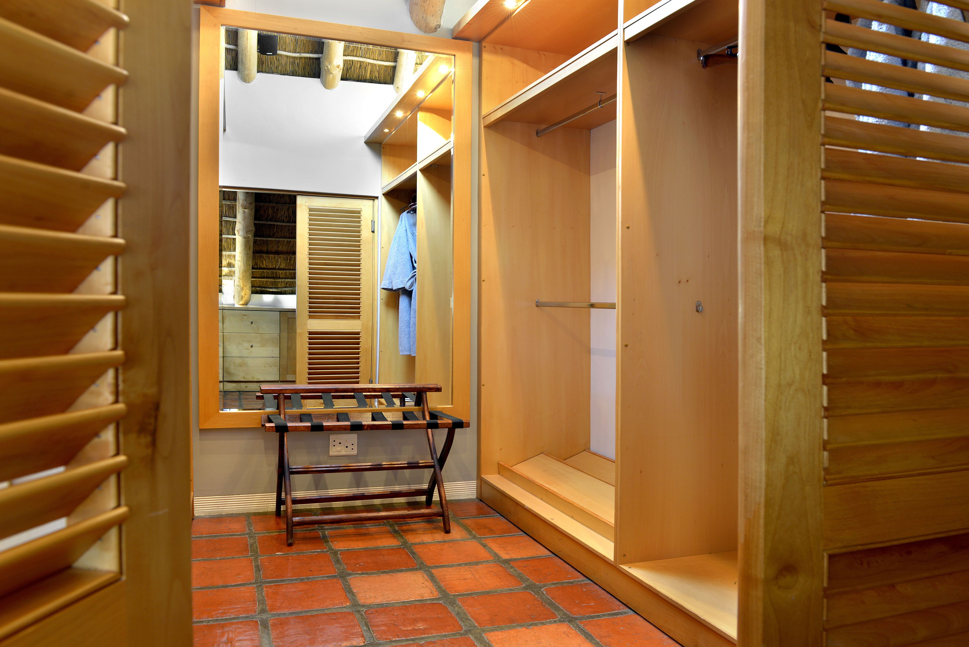 A walk-in closet with wooden shelving, a bench, and a hanging rack.