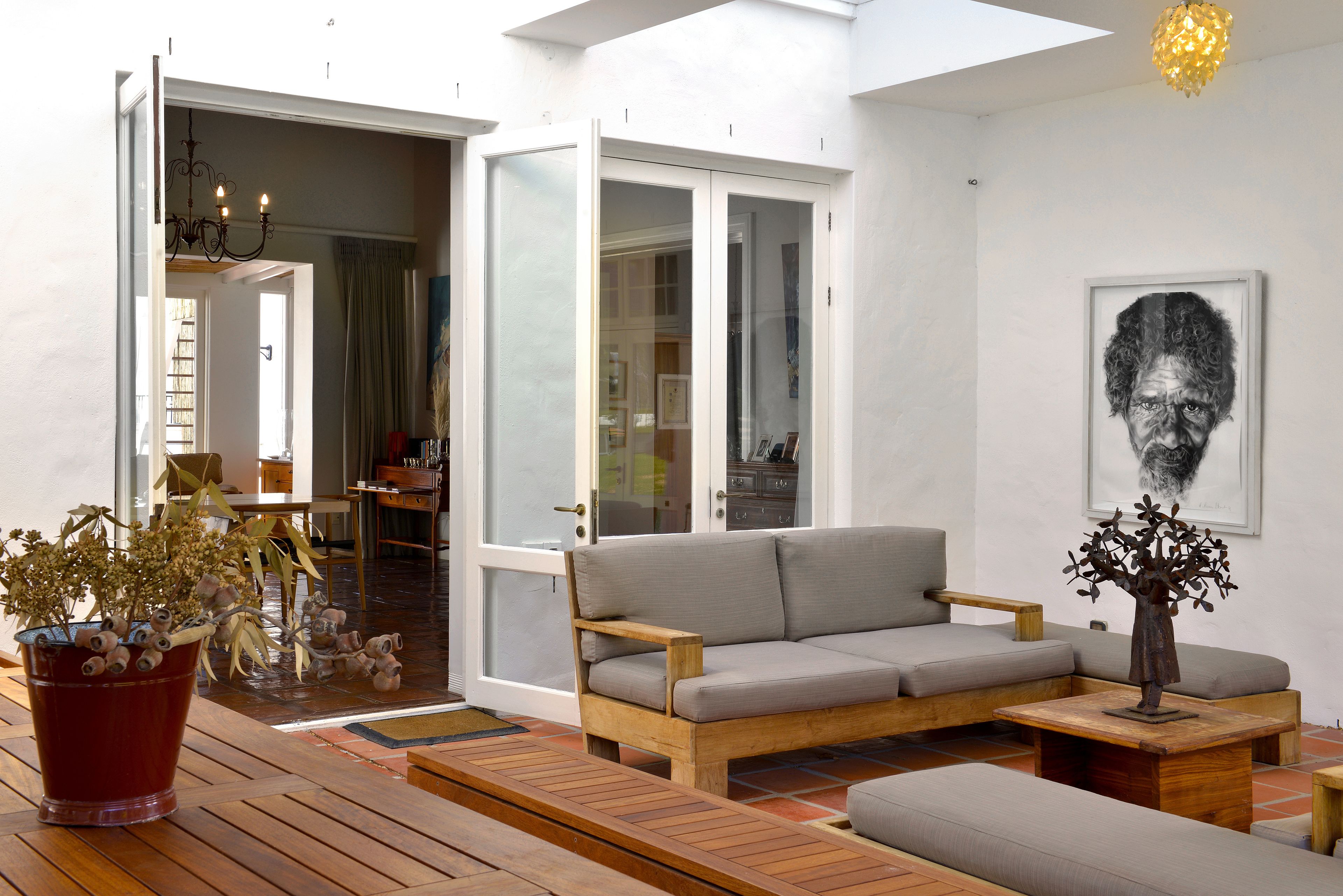 A modern living room with a wooden sofa, a dining table, and a potted plant.
