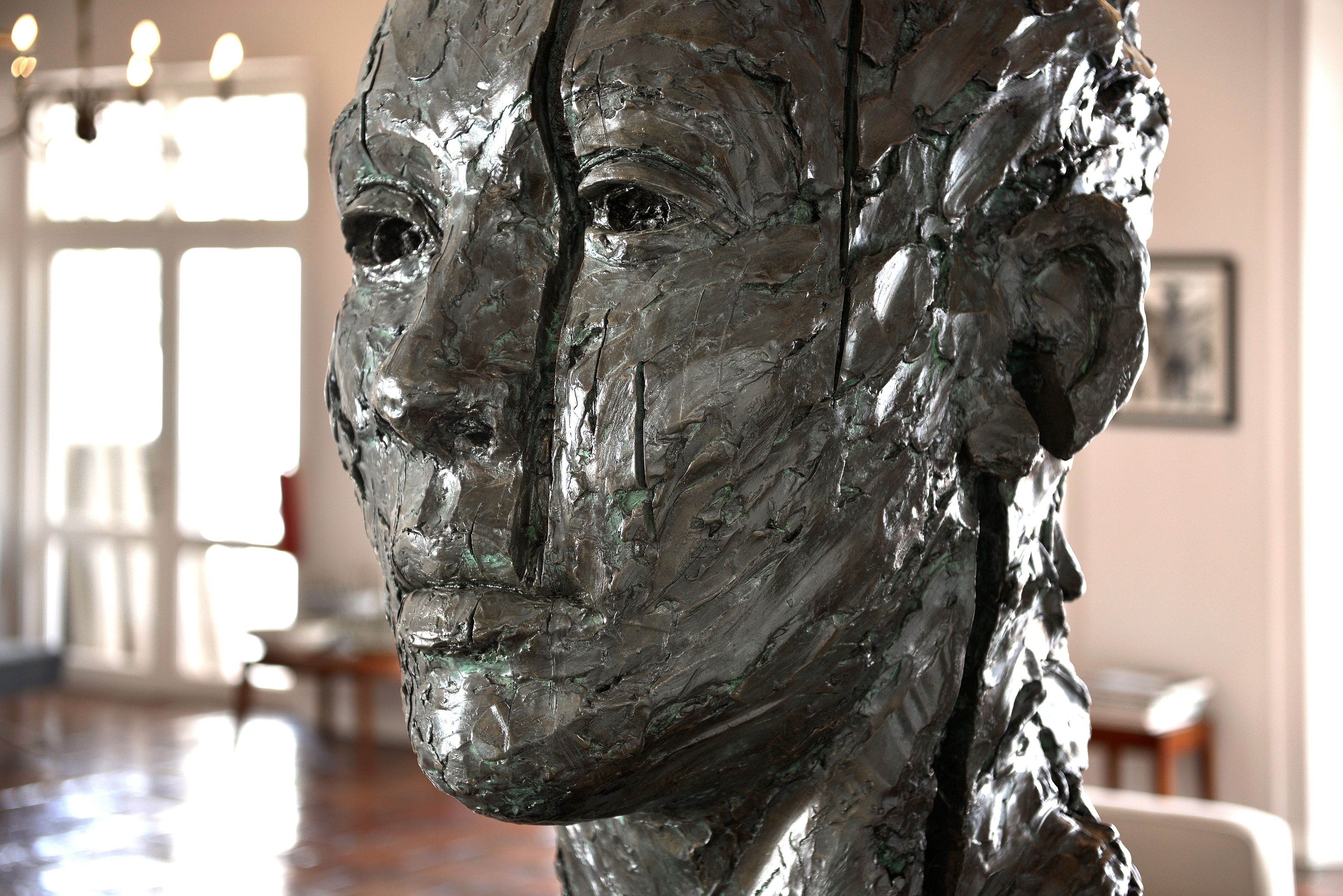 A sculpture in a well-lit room with a polished floor and a framed picture on the wall.