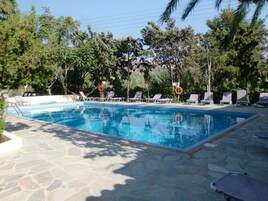Una piscina al aire libre de temporada, sombrillas