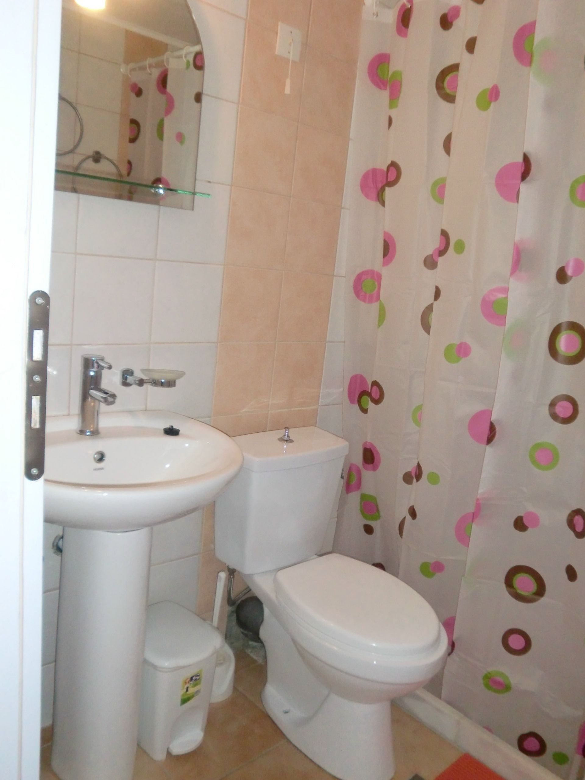 A bathroom with a toilet, sink, and shower curtain with a polka dot pattern.