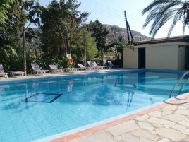 Una piscina al aire libre de temporada, sombrillas