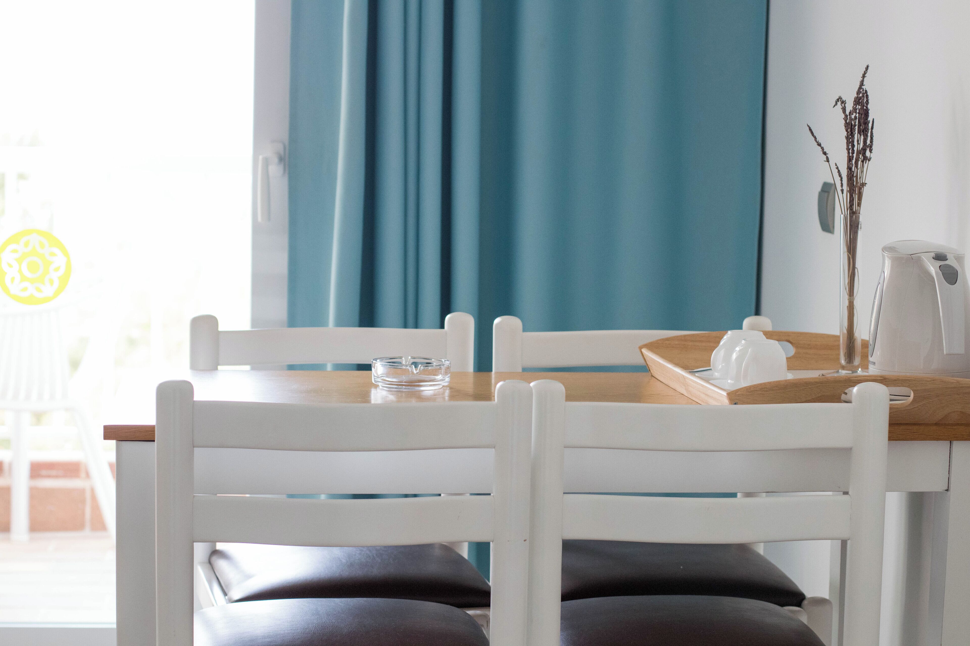 A dining area with a wooden table, white chairs, and a blue curtain.