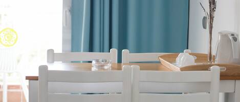 A dining area with a wooden table, white chairs, and a blue curtain.