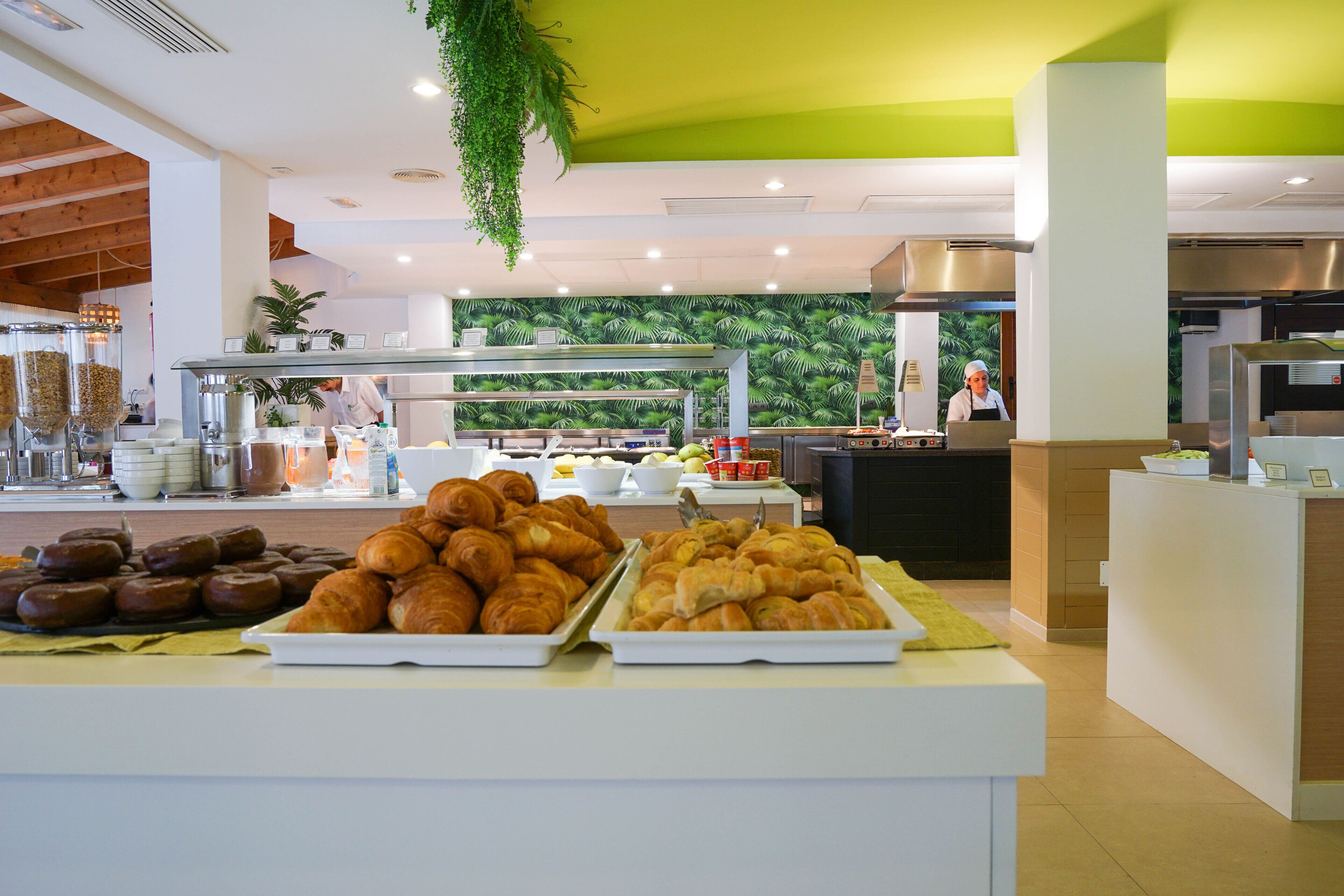Un espace buffet avec des plateaux de pâtisseries et, au fond, une cuisine.