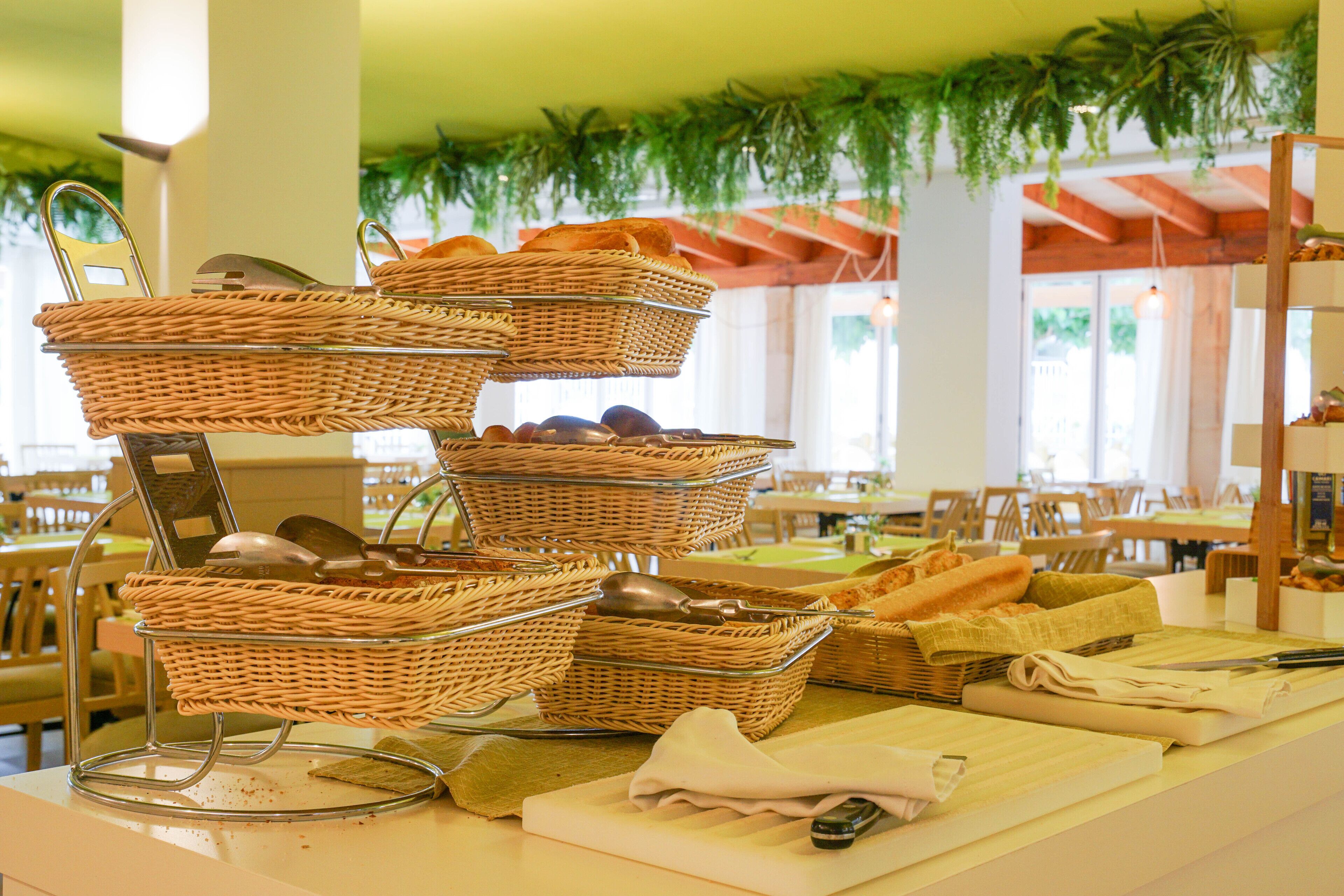 Un buffet composé de paniers en osier contenant du pain et des ustensiles, d'une planche à découper et d'une serviette.