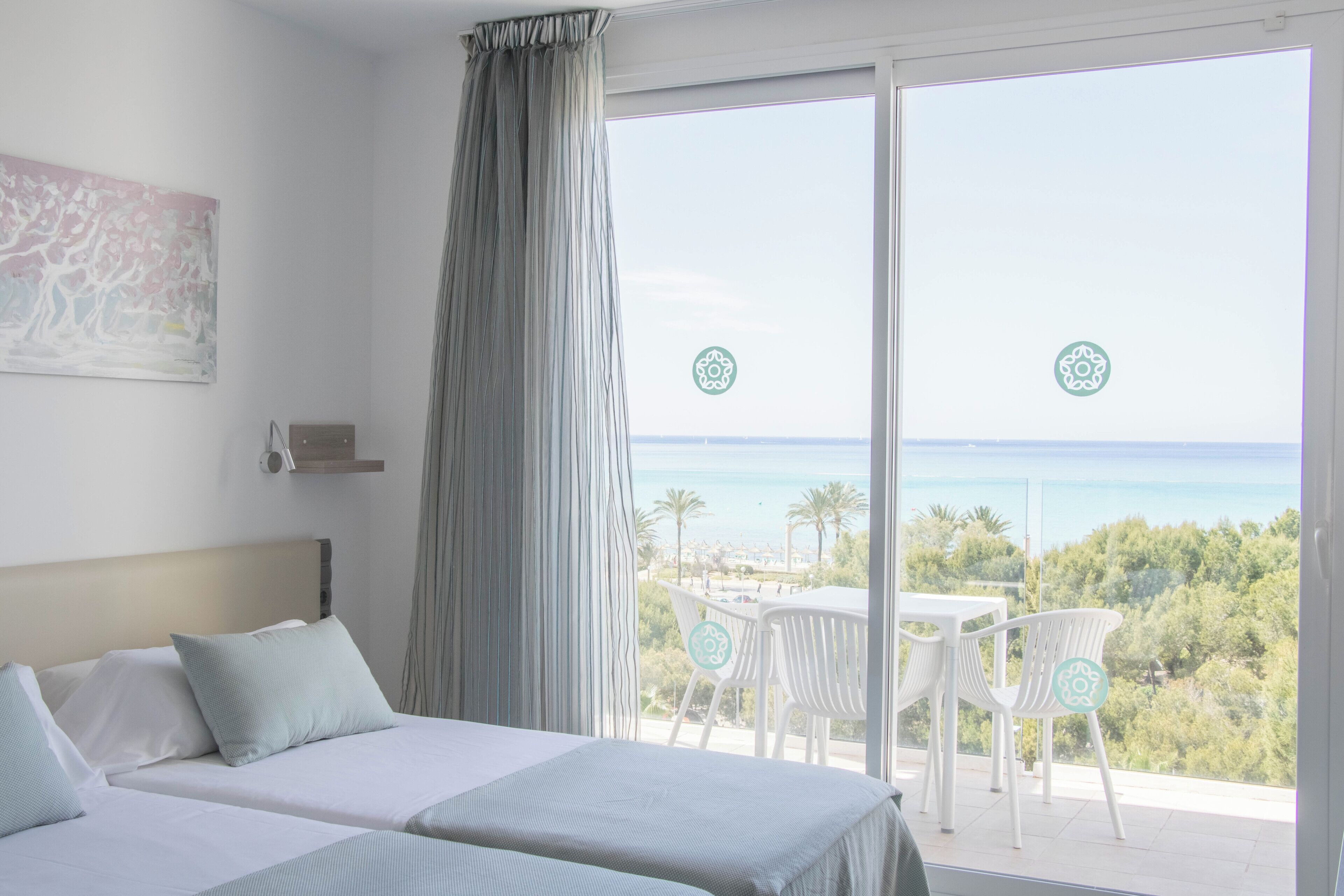 Une chambre d’hôtel avec un lit, une vue sur la mer et un balcon équipé de chaises.