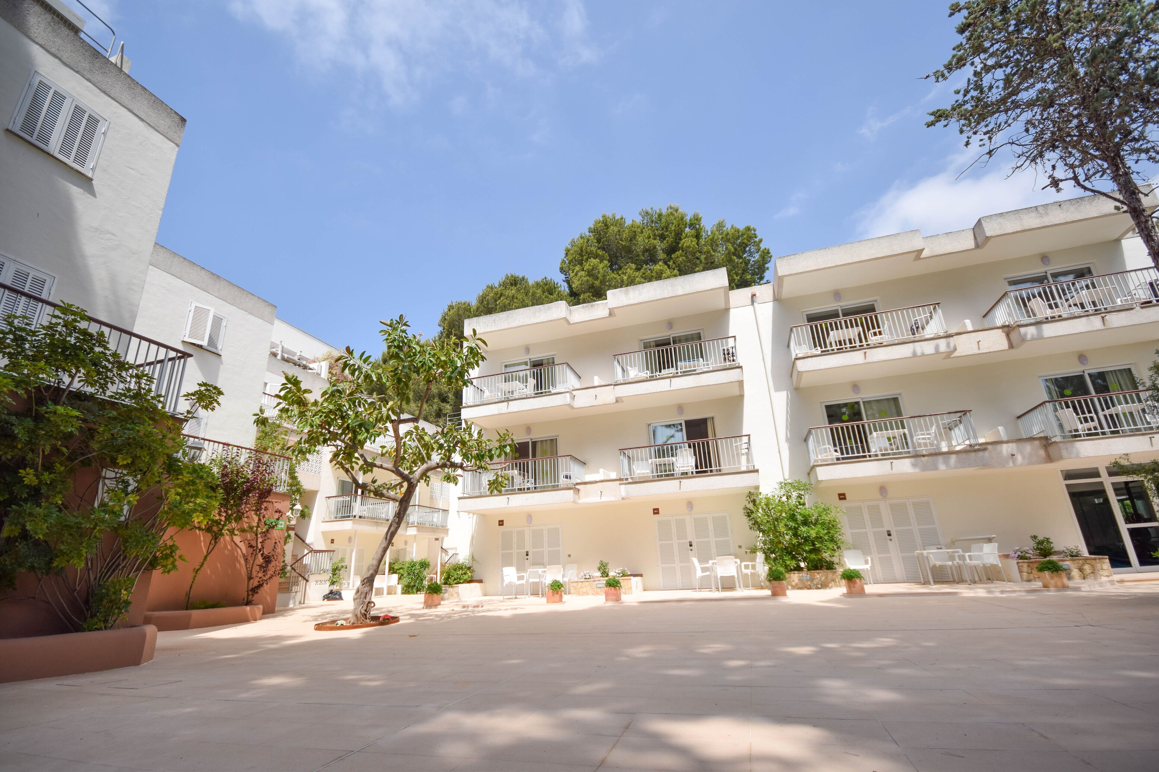 A courtyard with a building featuring balconies and potted plants.