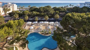 Un complexe hôtelier doté d’une piscine, de chaises longues et offrant une vue sur la mer.