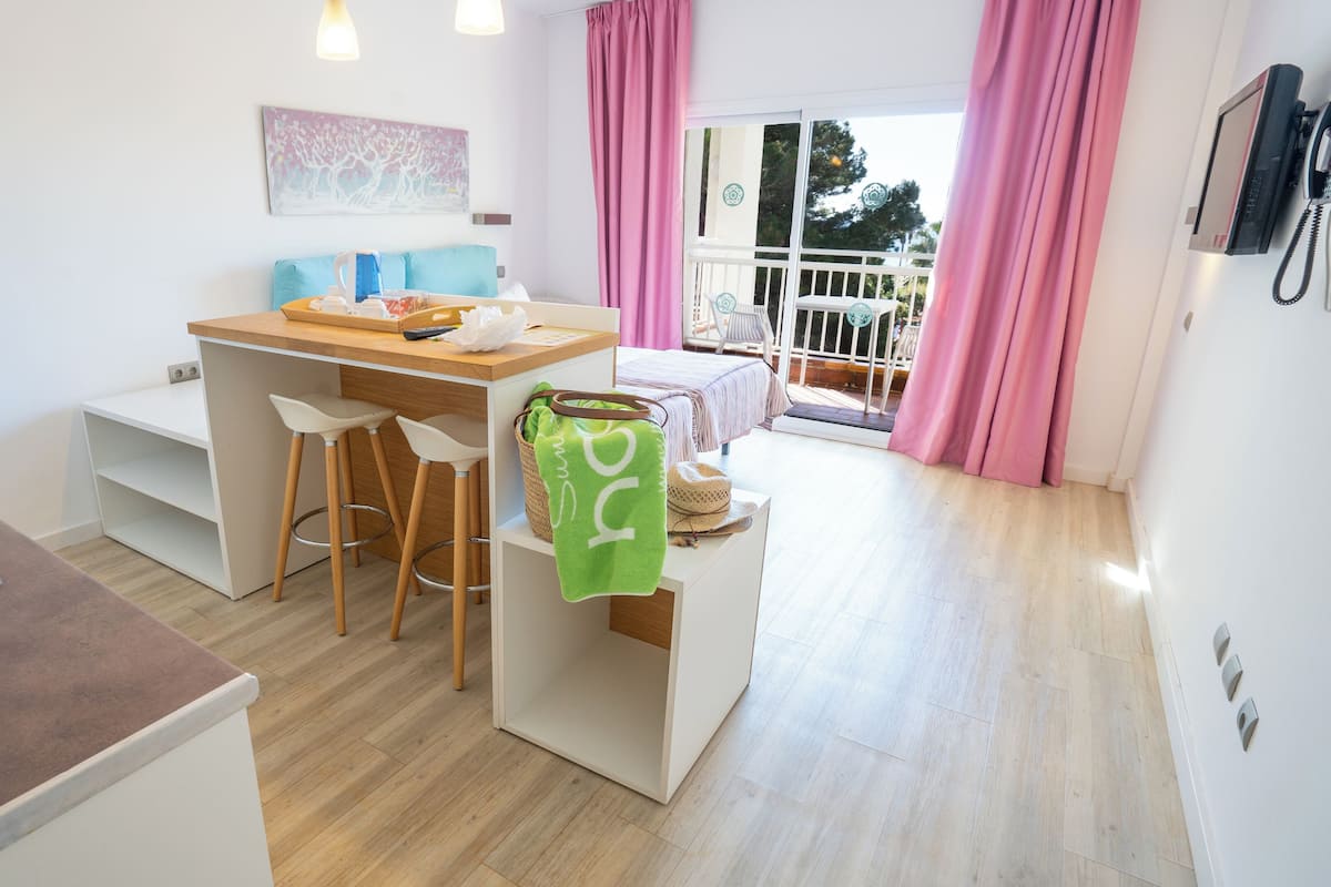 Cocina compacta con zona de comedor, un taburete pequeño y un banco con una toalla.