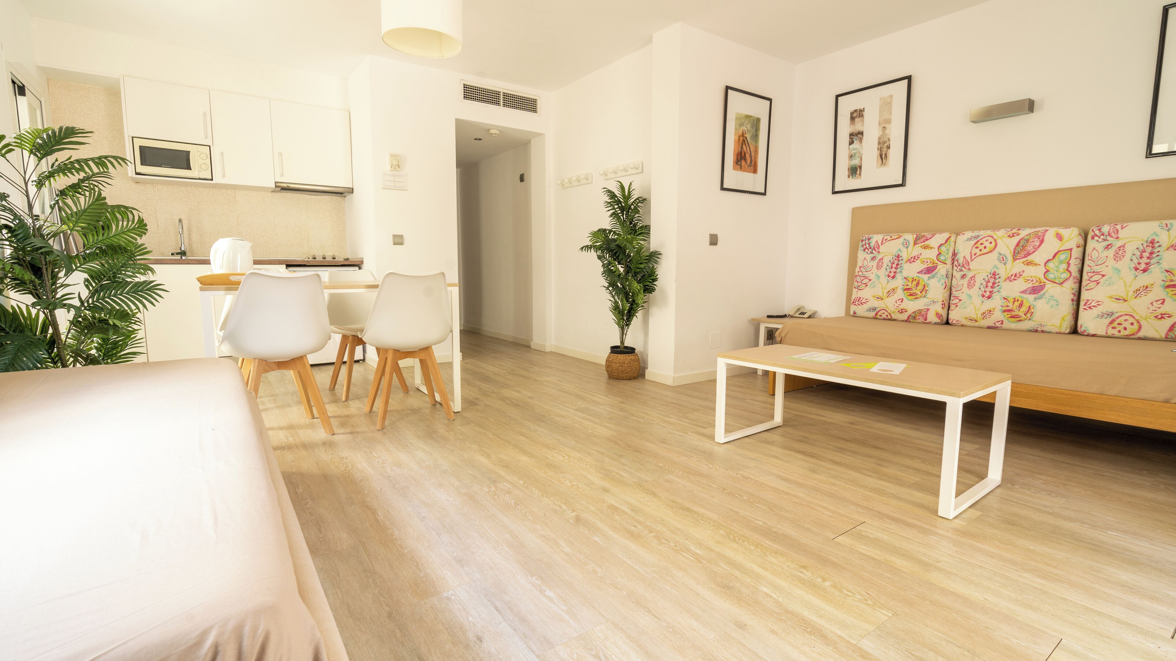 Una sala moderna con sofá, mesa de centro y comedor, con una cocina al fondo.