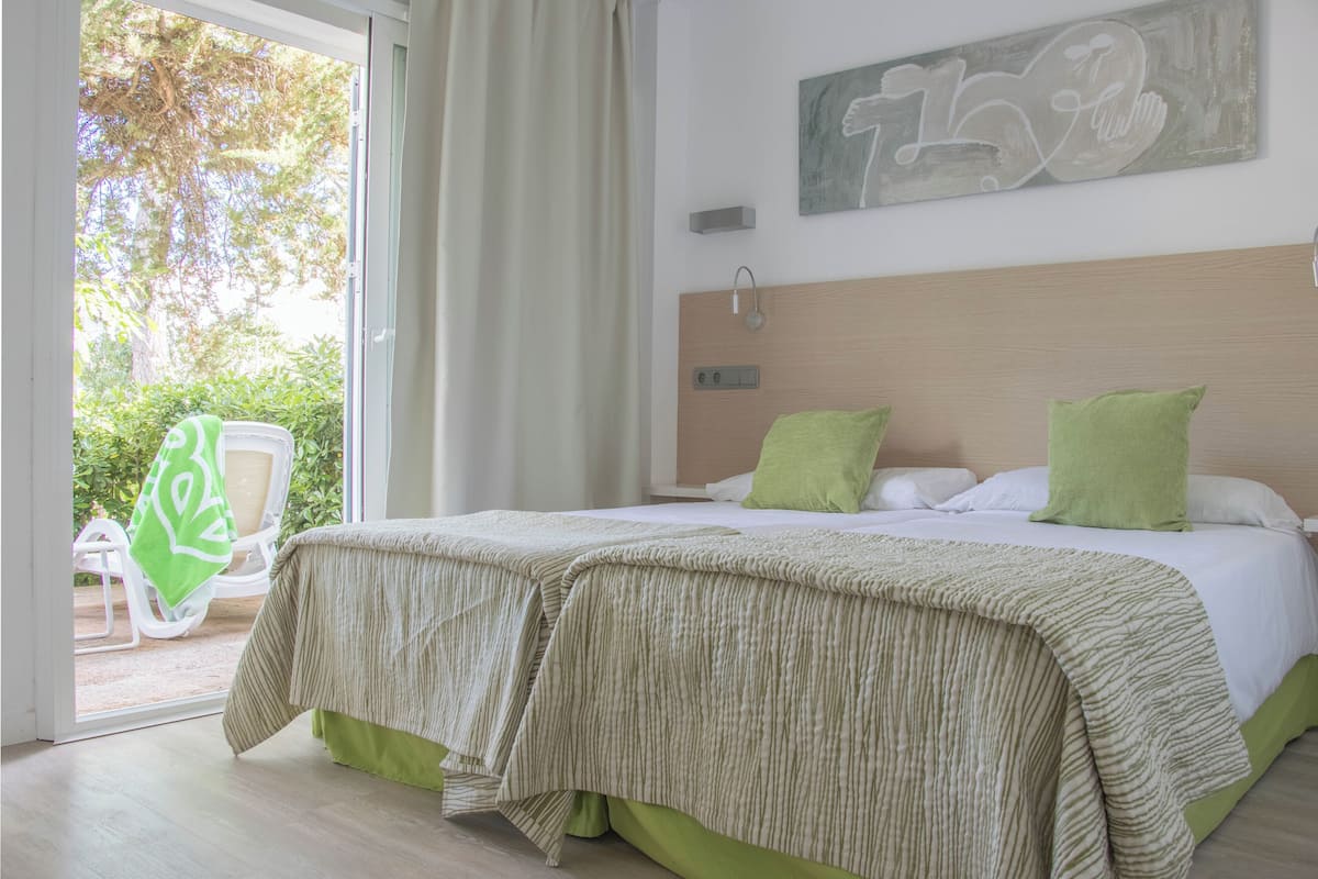 Un dormitorio con cama, ventana y vista a espacios verdes.