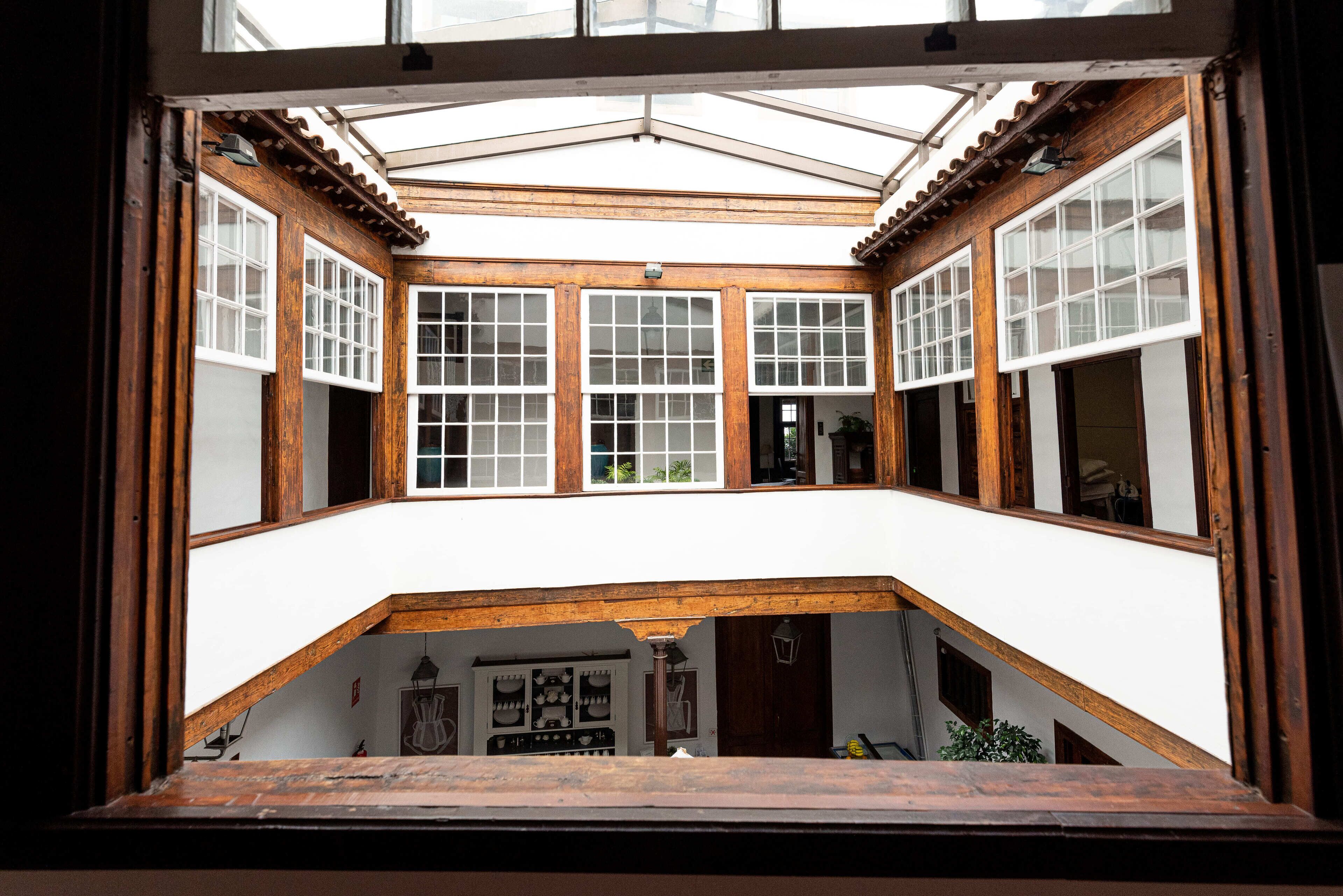 A covered courtyard with wooden beams and white walls, featuring multiple windows and a central open space.