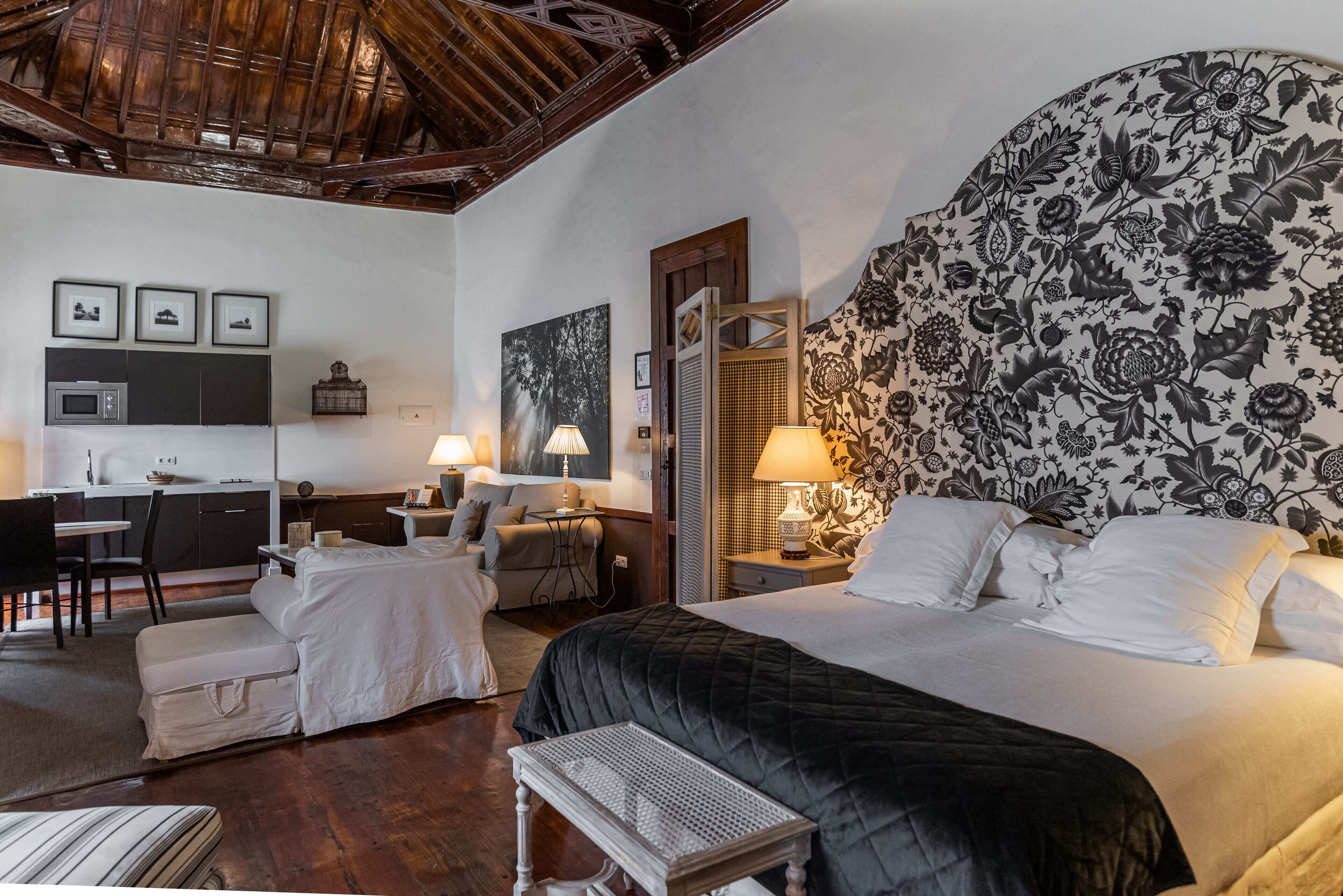 Una habitación de hotel con cama, escritorio, silla, mesita y sofá.