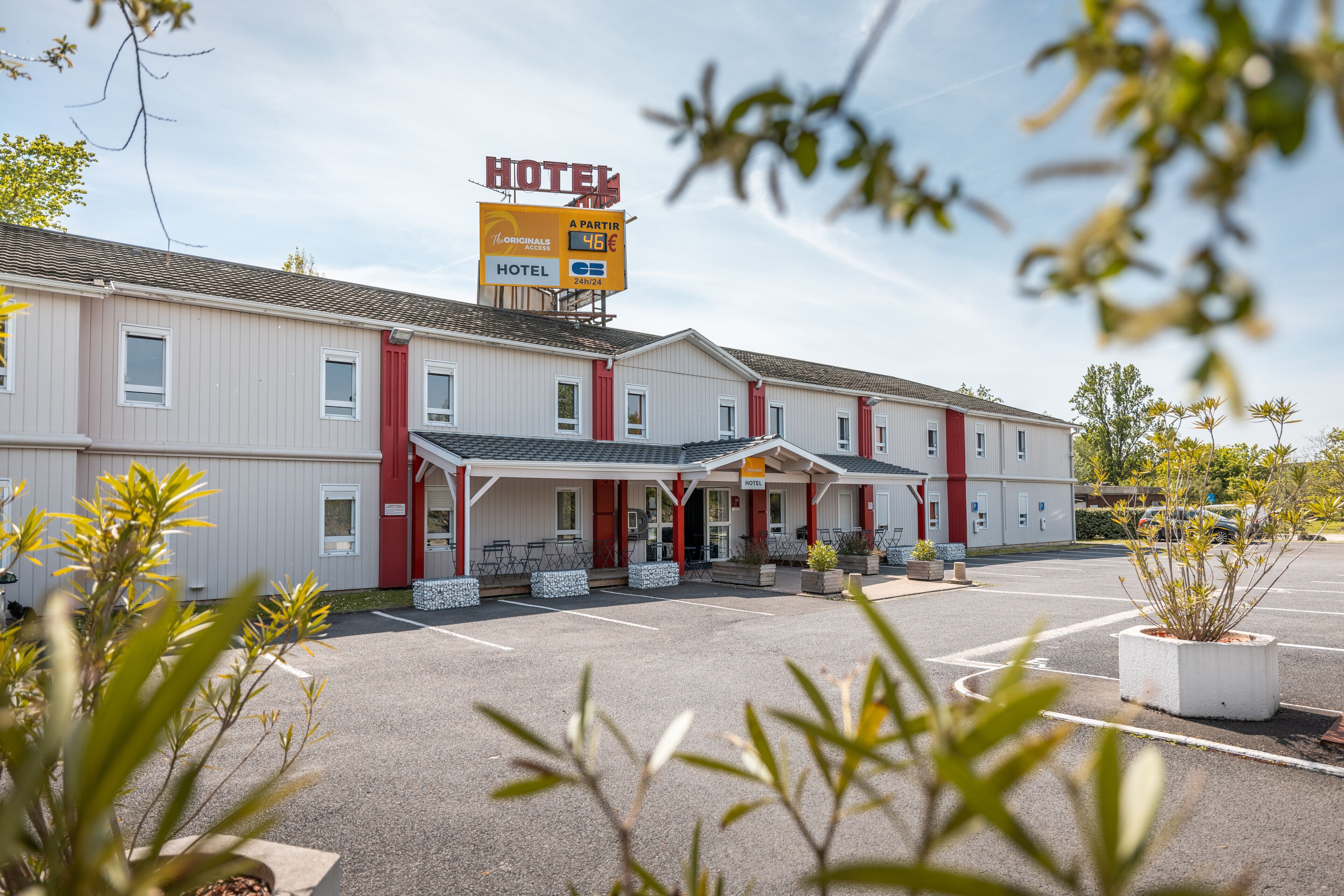 A hotel with a covered entrance, outdoor seating, and a parking lot.