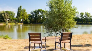 Two wooden park benches facing a calm lake with trees in the background. - The Originals Access, Hôtel Bordeaux Lac (Bruges)