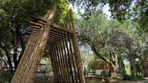 A bamboo structure in a park with trees and a lamp post. - Eilon TravelHotel (Mateh Asher)