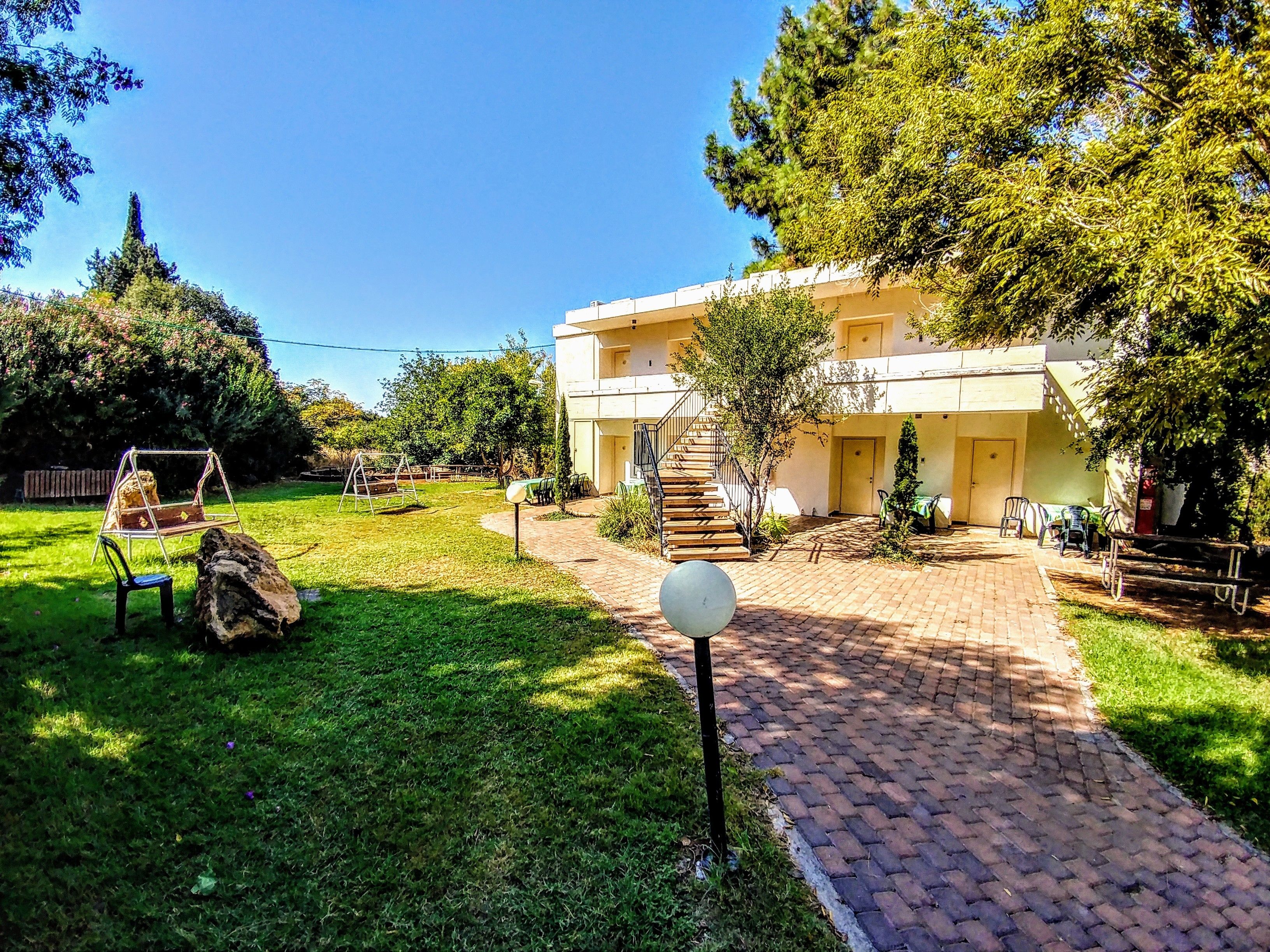 A courtyard with a swing set, a brick pathway, and a building with a staircase leading to an upper level.