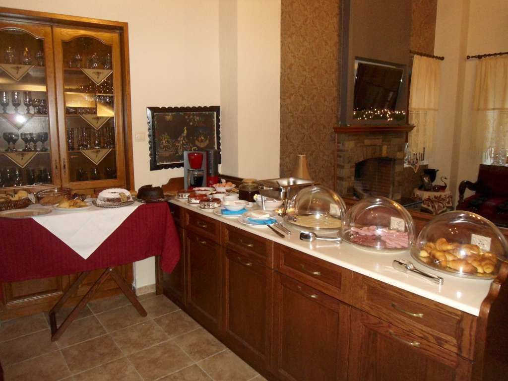 A buffet setup with various food items and glassware on a counter, wooden cabinets, and a fireplace.