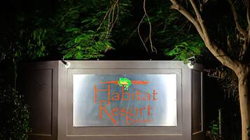 A sign for Habitat Resort with a logo and name.