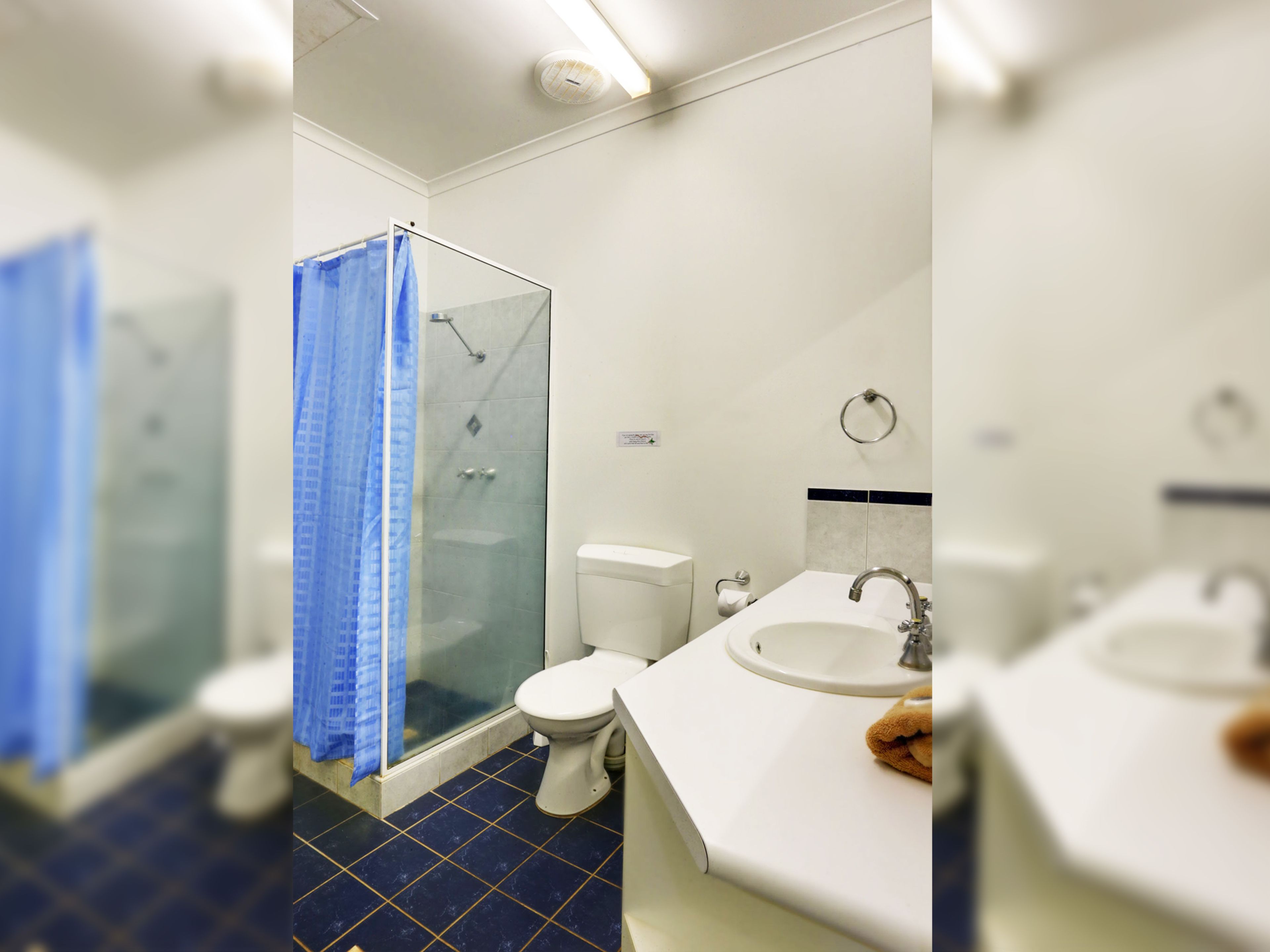 Een badkamer met een douchecabine van glas, toilet en wastafel.