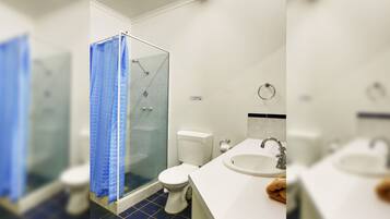 Een badkamer met een douchecabine van glas, toilet en wastafel.