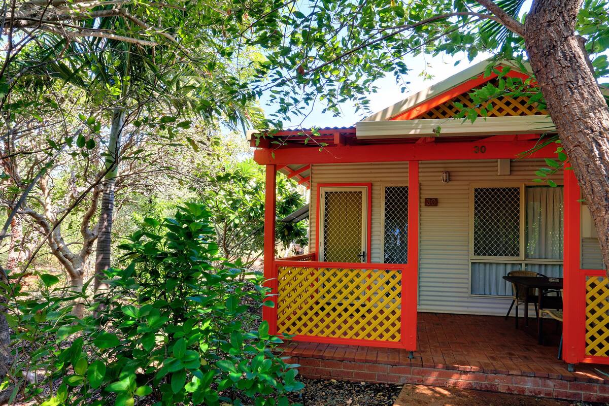 A small, single-story building with a red and yellow exterior, a covered porch, and a number '30' sign.