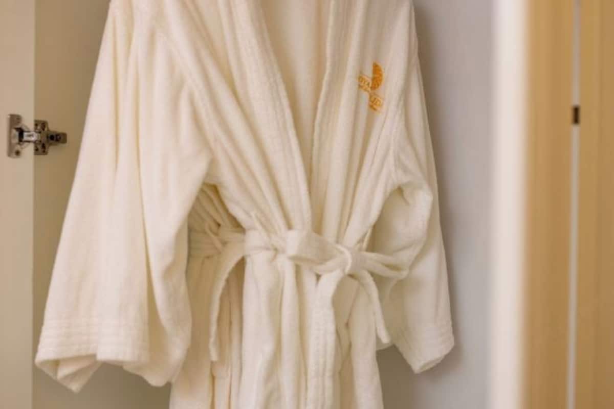 A white bathrobe hanging on a door handle.