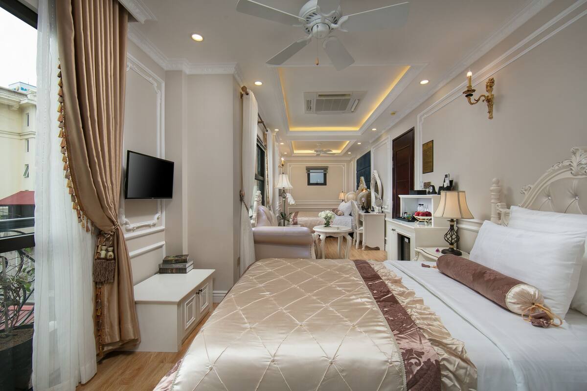 A hotel room with a large bed, a TV, a desk, and a chair.