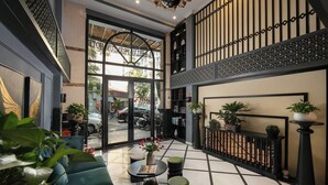 Eine geräumige Lobby mit hoher Decke, einem zentralen Sitzbereich mit Couchtisch und Blick auf die Straße.