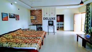 Habitación de hotel con una cama grande, un escritorio con televisor y una kitchenette.