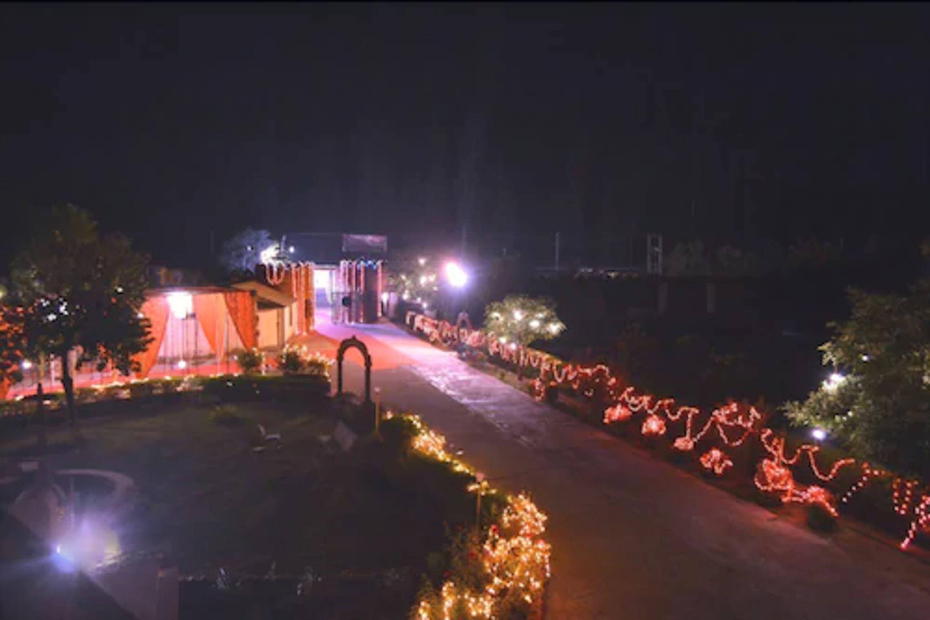 A nighttime view of a street with illuminated decorations and a building with a red roof.