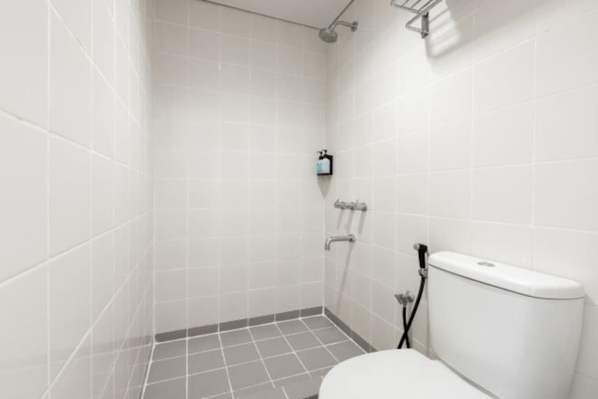 A small, tiled bathroom with a toilet, a shower, and a towel rack.