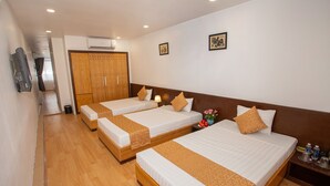 A hotel room with three single beds, wooden headboards, white linens, and a wooden wardrobe. - Rendez Vous Hotel (Hanoi)