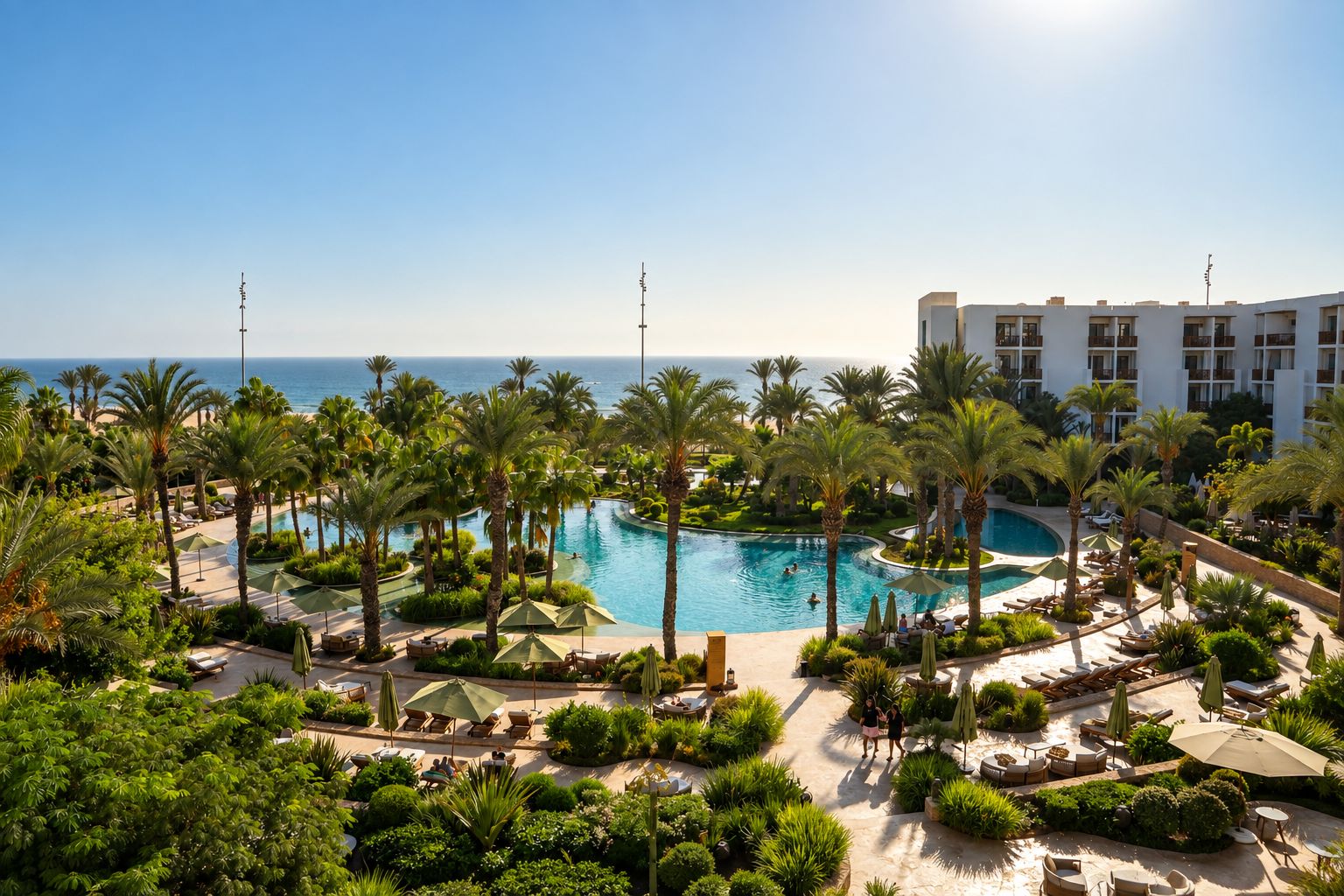 A resort with a large pool surrounded by palm trees and lounge chairs.