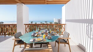 A dining area with a table set for breakfast, overlooking a beach.