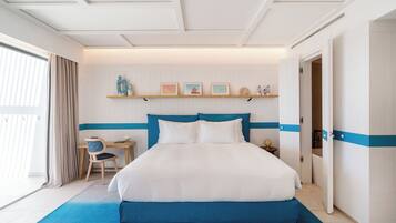 Habitación de hotel con una cama grande, un escritorio y una silla. Se ve una repisa con objetos decorativos sobre la cama.
