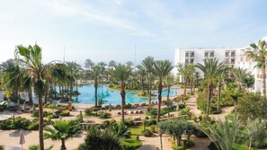 A resort with multiple swimming pools surrounded by palm trees and greenery, a large building with balconies, and a clear sky. - The View Agadir (Agadir)