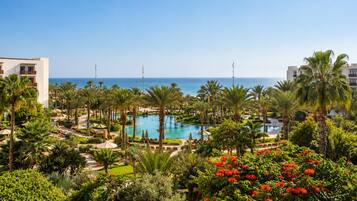 Un resort con piscina central, palmeras y vista al océano.