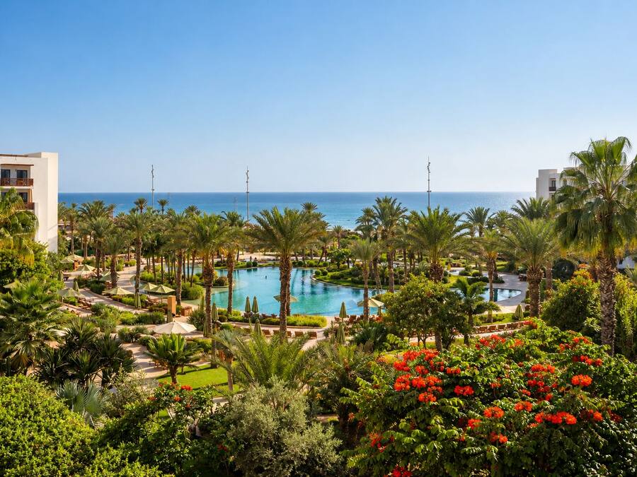 Un resort con piscina central, palmeras y vista al océano.