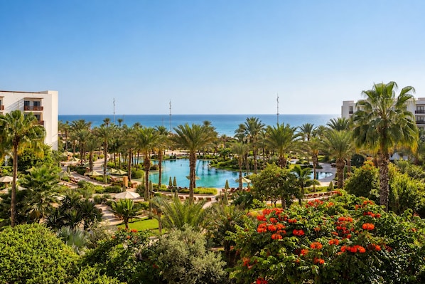 A resort with a central swimming pool, palm trees, and a view of the ocean. - The View Agadir (Agadir)