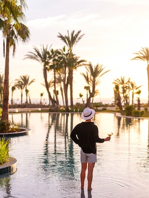 A person standing by a pool with palm trees in the background. - The View Agadir (Agadir)
