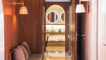 A hallway leading to a bathroom with a sink, mirror, and towel rack.