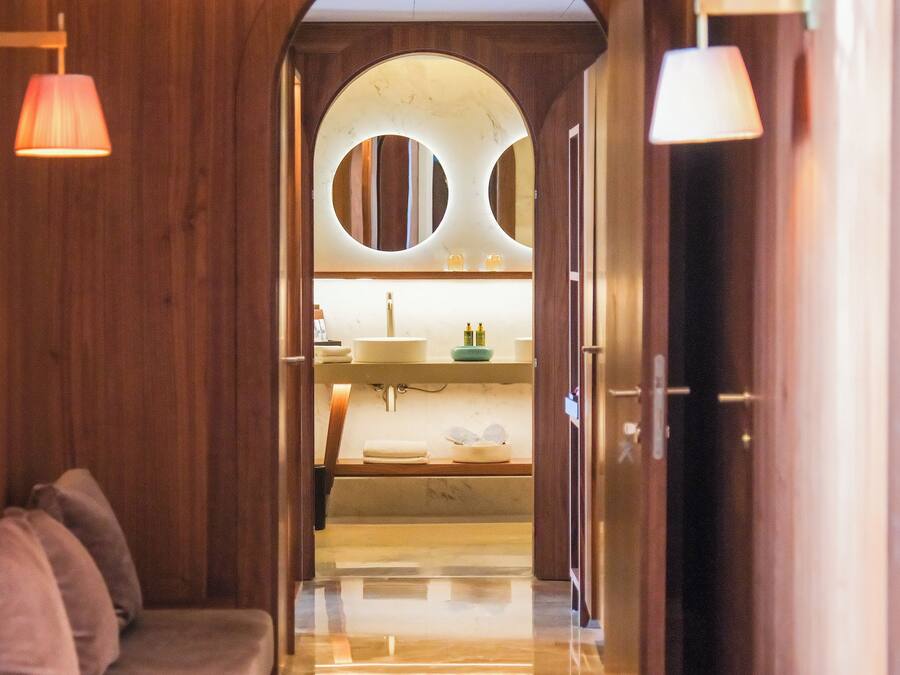 A hallway leading to a bathroom with a sink, mirror, and towel rack.