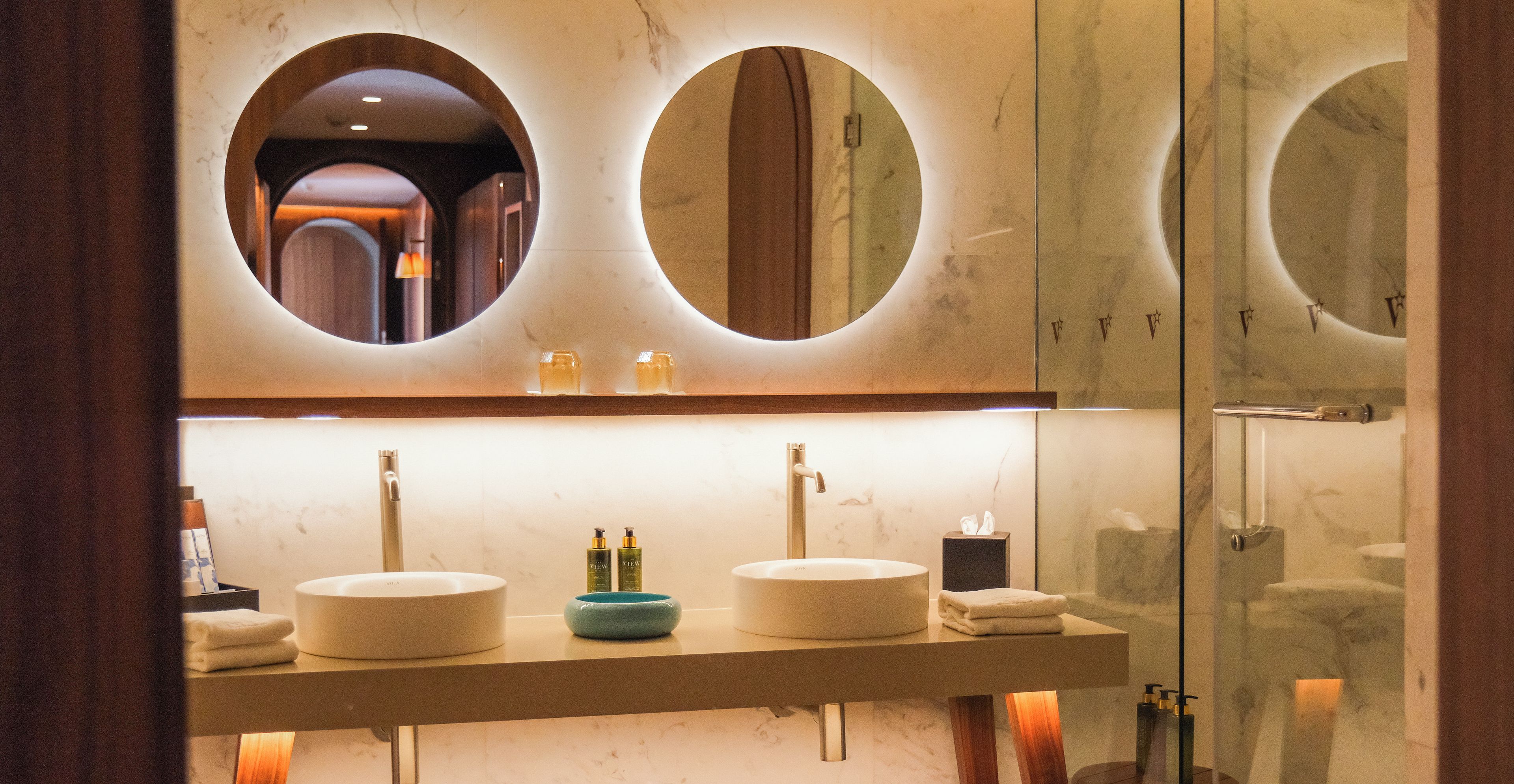 Un baño con dos espejos redondos, un lavabo y tocador.