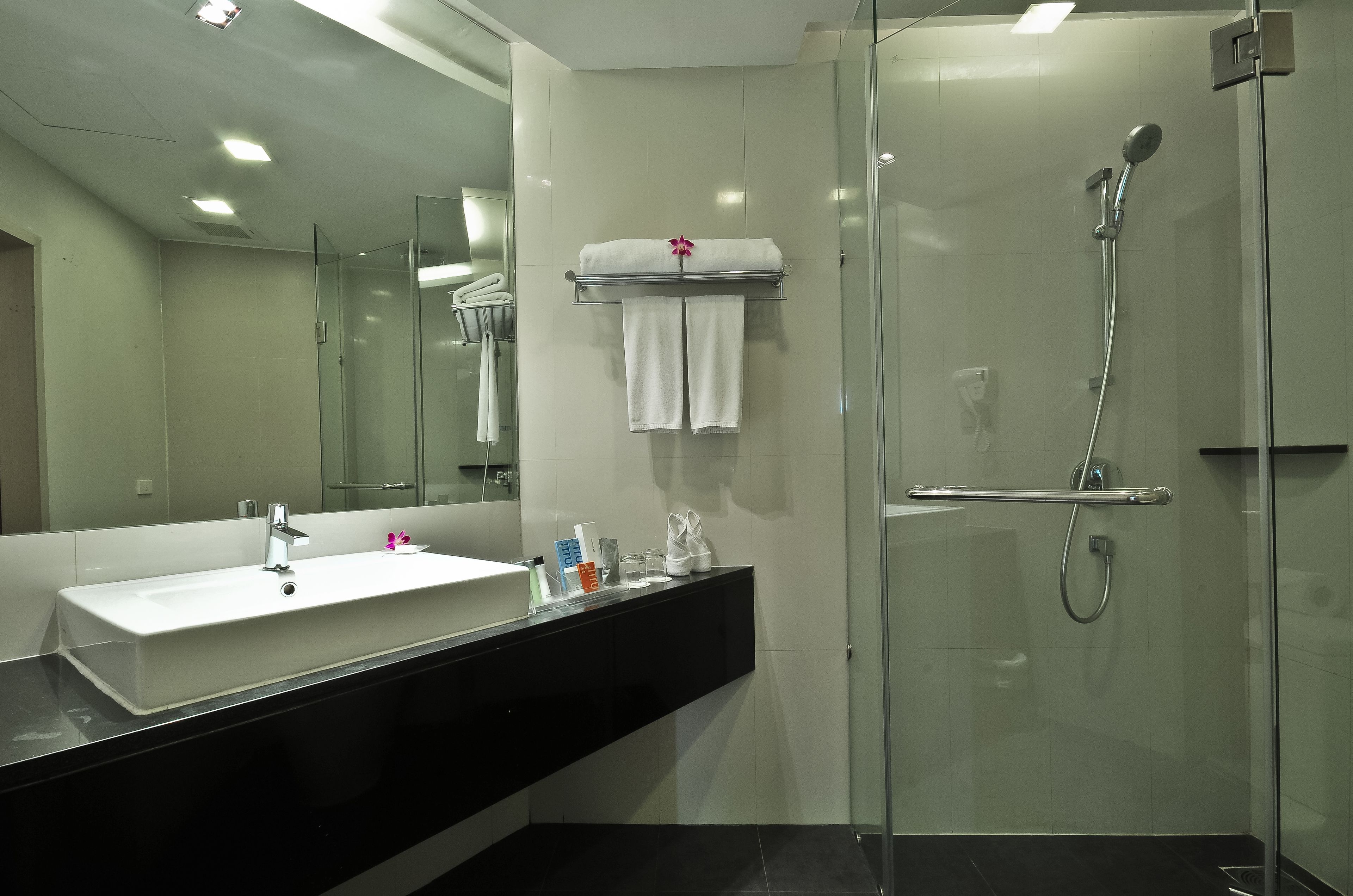 A modern bathroom with a glass-enclosed shower, a white sink, and a black countertop.