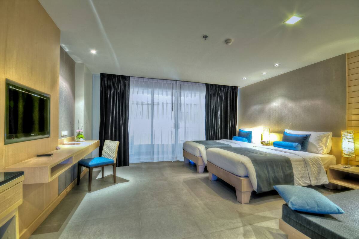A modern hotel room with a large bed, a desk, and a TV.