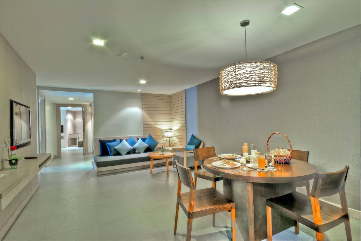 A modern dining area with a round table, chairs, and a hanging light fixture.