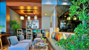 A modern hotel lobby with a bar area, seating arrangements, and a large window with greenery. - ASHLEE Heights Hotel Patong (Patong)
